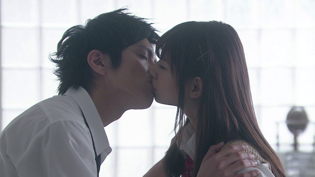 A boy and a girl in high-school uniforms kiss